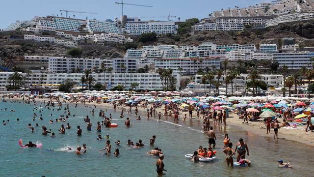 Tourists bathe and sunbathe on the beach of Puerto Rico in the south of the island of Gran Canaria