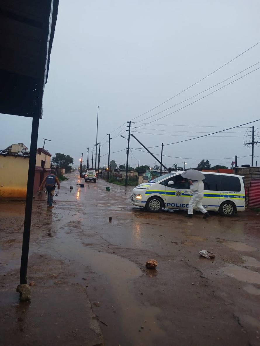 Law enforcement officials walk at the scene after an early morning shooting in Bekkersdal township south-west of Johannesburg