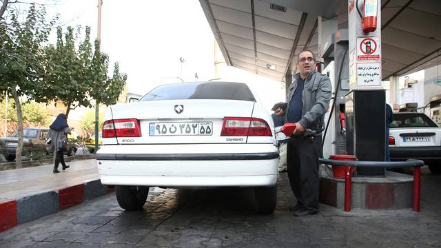 FILE PHOTO: A man fills up his car's tank at a petrol station, after fuel price increased in Tehran