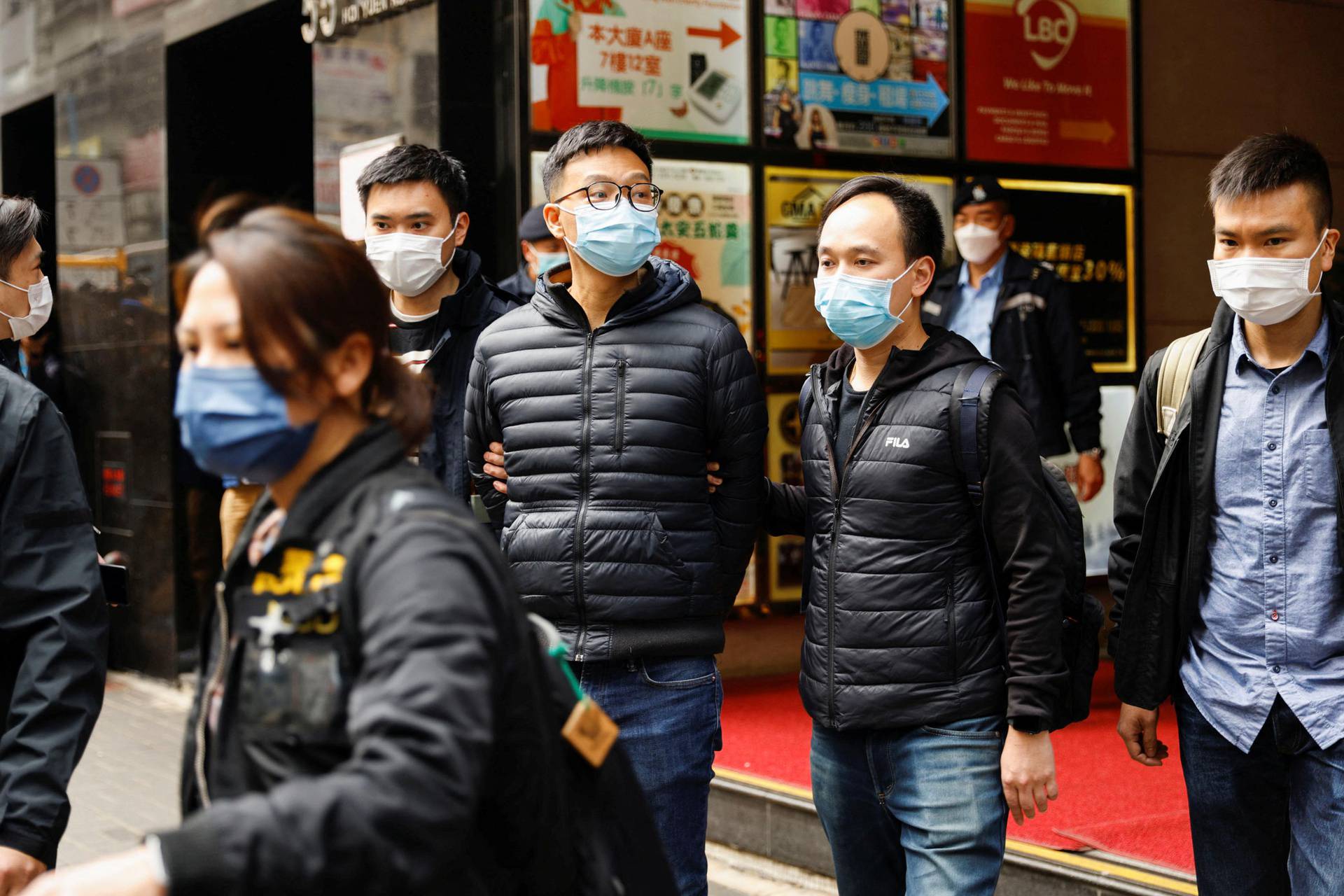 Stand News acting chief editor Patrick Lam is escorted by police as they leave after the police searched his office in Hong Kong