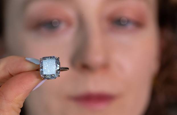 A Sotheby’s staff holds "The Mediterranean Blue" diamond during an auction preview in Geneva
