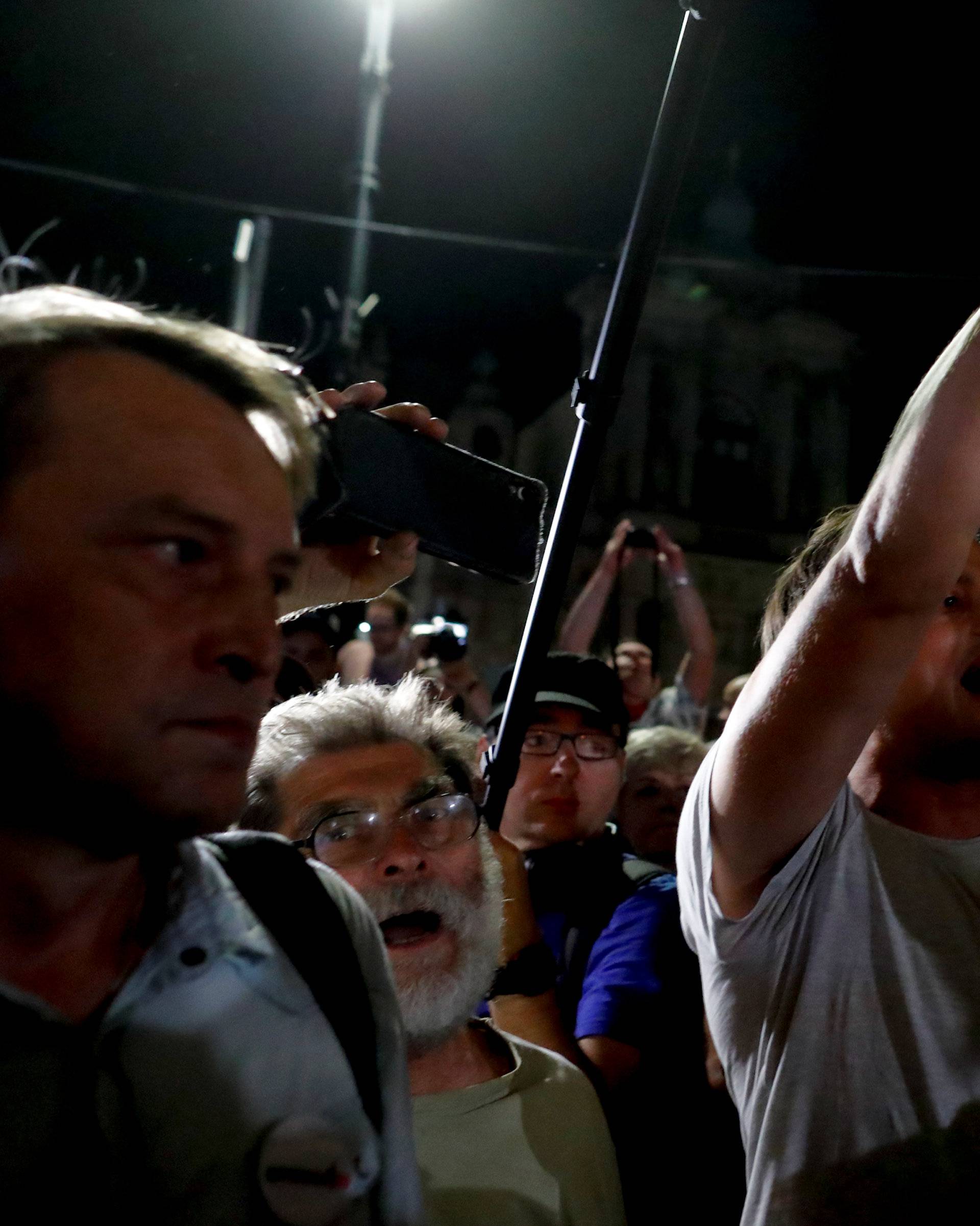 People chant slogans as a police officer guards during the "Chain of lights" protest against judicial overhaul in front of the Presidential Palace in Warsaw