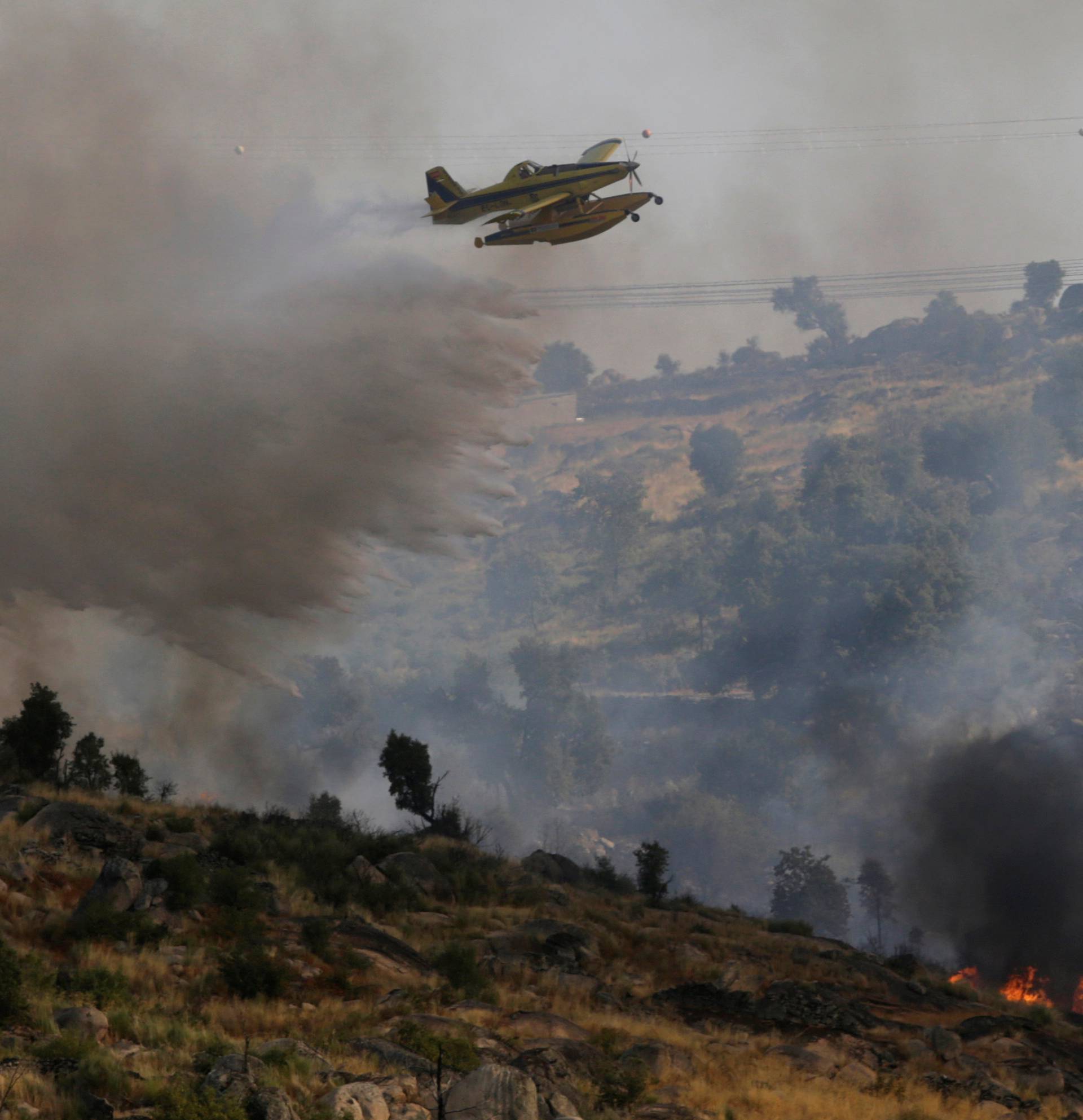 An aircraft drops water over a forest fire near Lagoaca