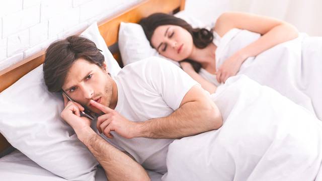 Man cheater talking privately on cellphone in family bed