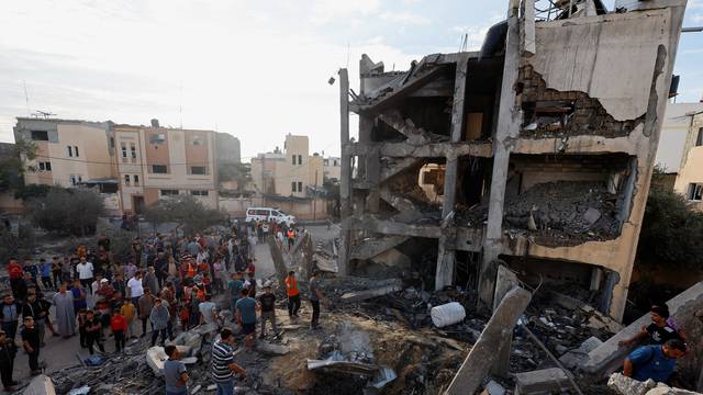 Palestinians search for casualties under the rubble of a building destroyed by Israeli strikes in Khan Younis