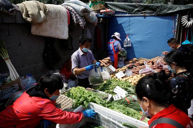 A vegetable stall vendor wearing a face mask attends to customers at an outdoor market in Beijing, following the novel coronavirus disease (COVID-19) outbreak