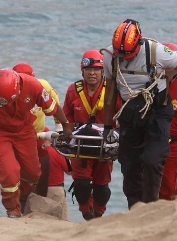 Rescue workers carry victims after a bus crashed with a truck and careened off a cliff along a sharply curving highway north of Lima,