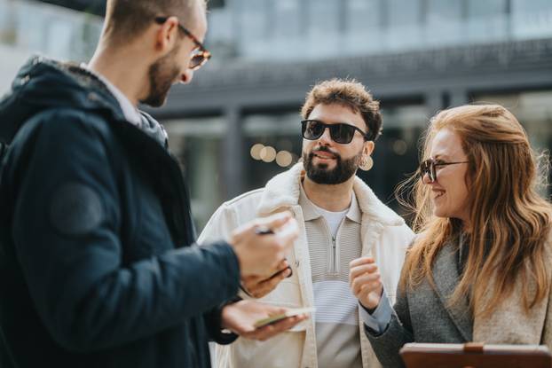 Group of Friends Smiling and Talking Outdoors on a Clear Day