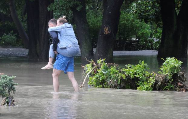 People cross a flooded street following heavy rainfall in Yalta