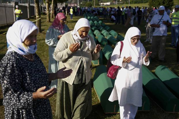 Women pray near coffins of their relatives, who are newly identified victims of the 1995 Srebrenica massacre, which are lined up for a joint burial in Potocari near Srebrenica