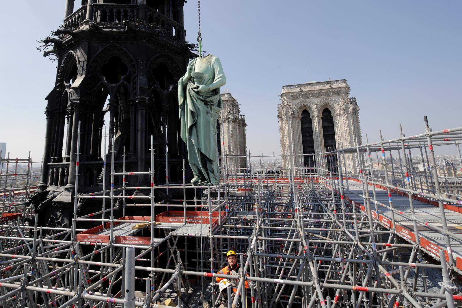 FILE PHOTO: A statue of Saint John is removed from the spire of Notre Dame cathedral by a crane before restoration work, in Paris