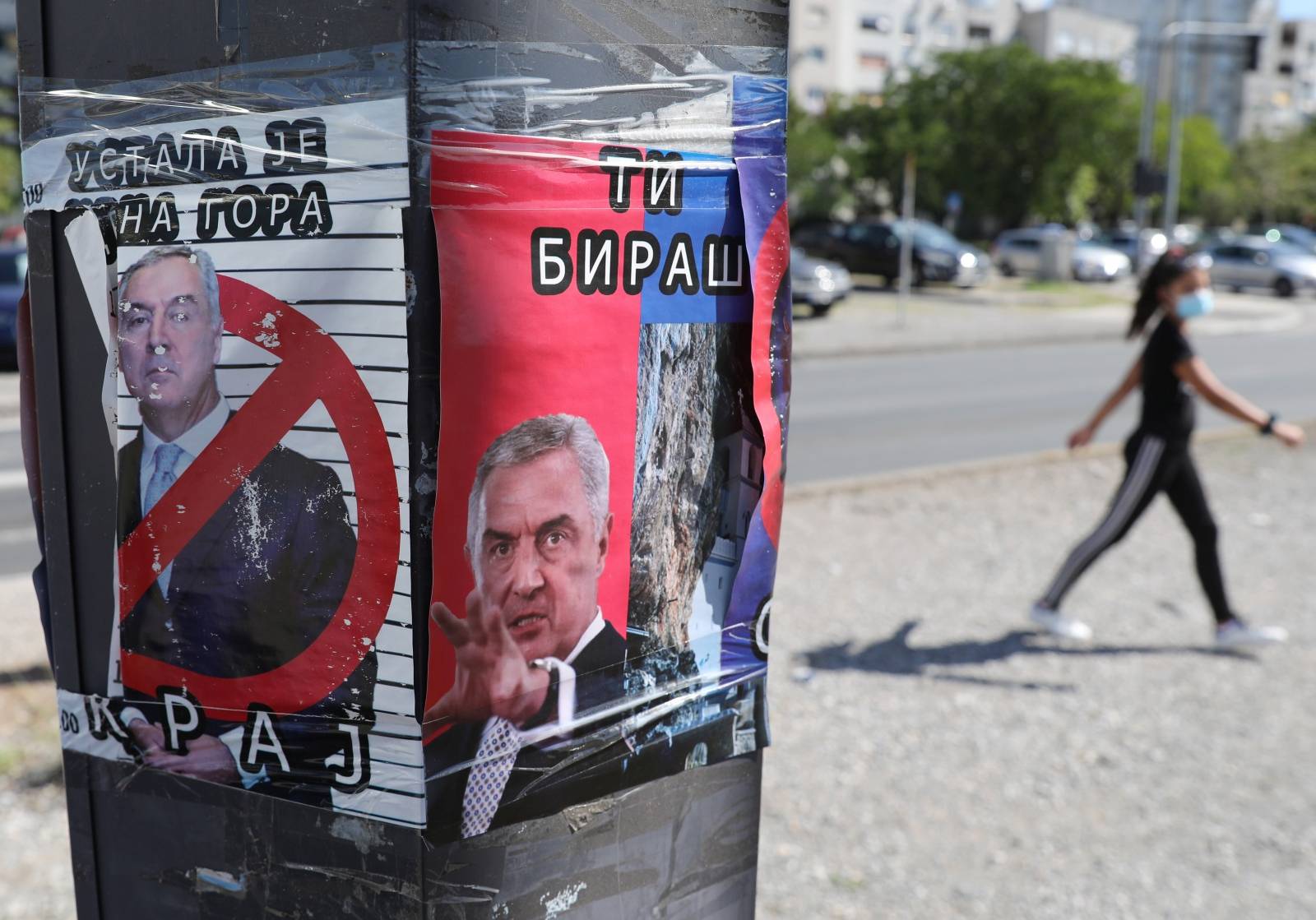 A woman walks near an anti Montenegro President Milo Djukanovic poster ahead of Montenegrin Assembly election in Podgorica