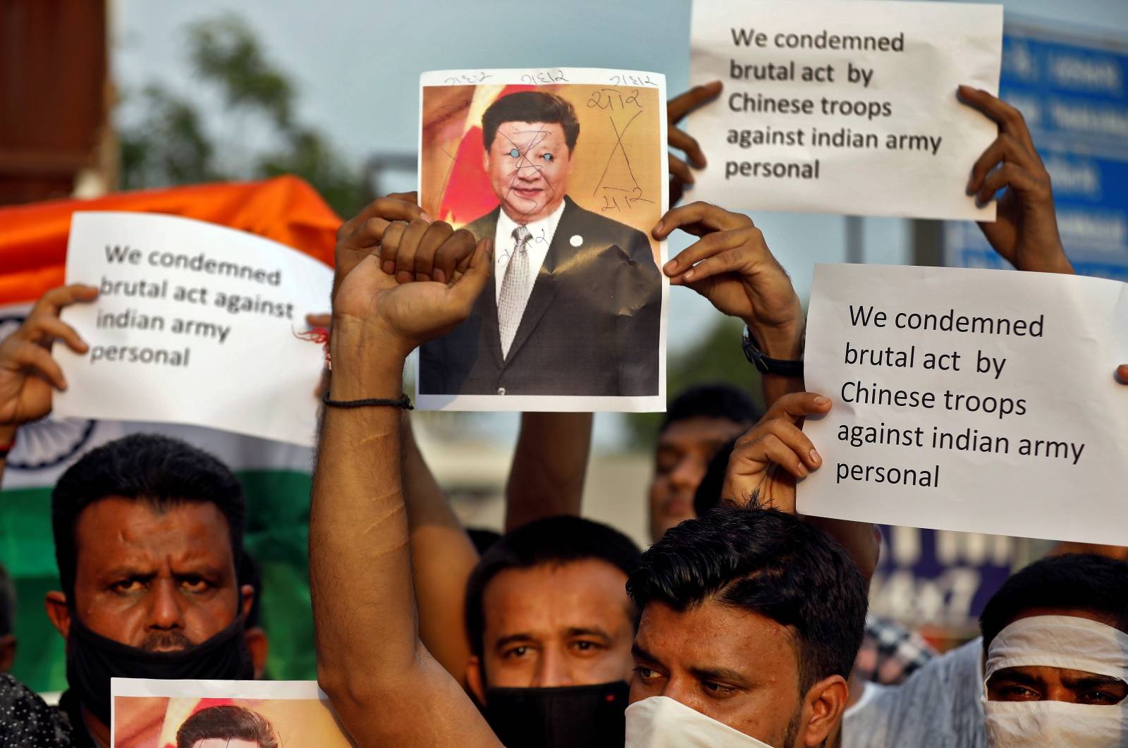 Demonstrators hold placards and a defaced poster of Chinese President Xi Jinping as they shout slogans during a protest against China, in Ahmedabad