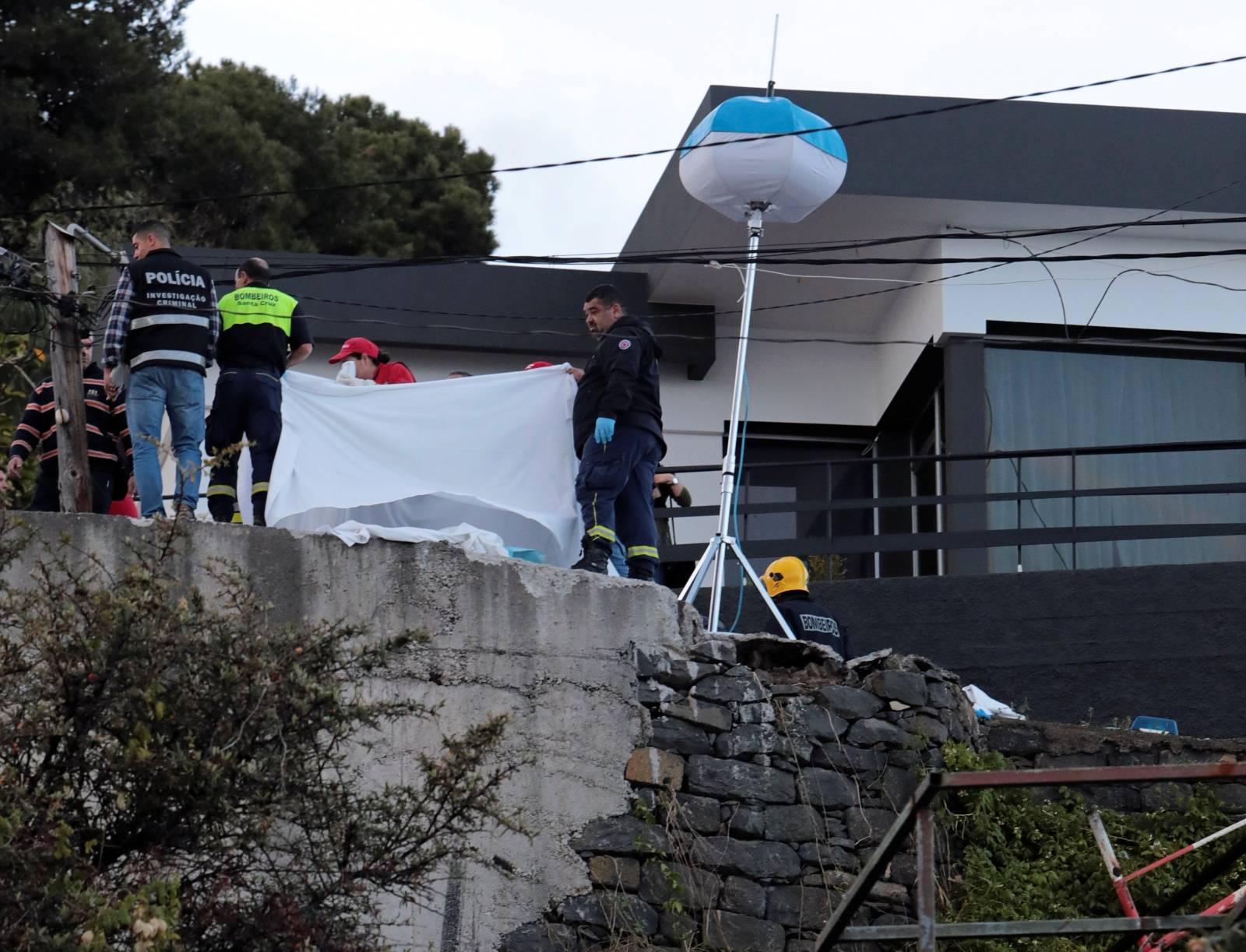 Rescue workers use blanket to cover bodies at the scene of a bus accident in Canico