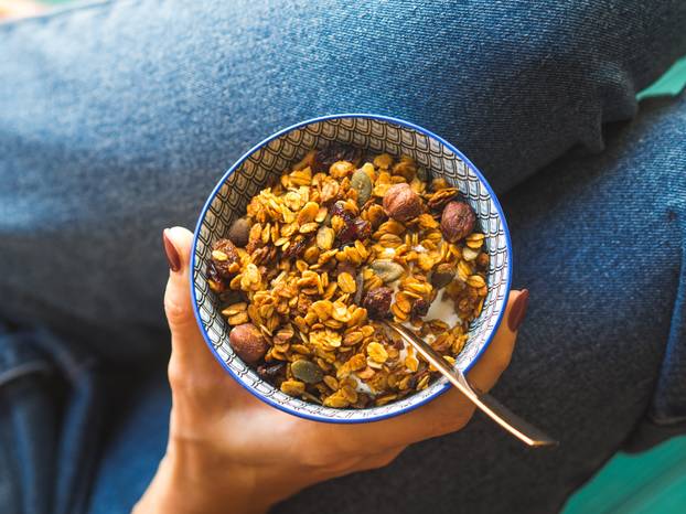 Girl in jeans eating home made granola bowl