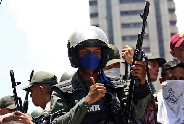 A soldier gestures while riding on top of a car with fellow soldiers and supporters of Venezuelan opposition leader Juan Guaido, during anti-government protests, in Caracas