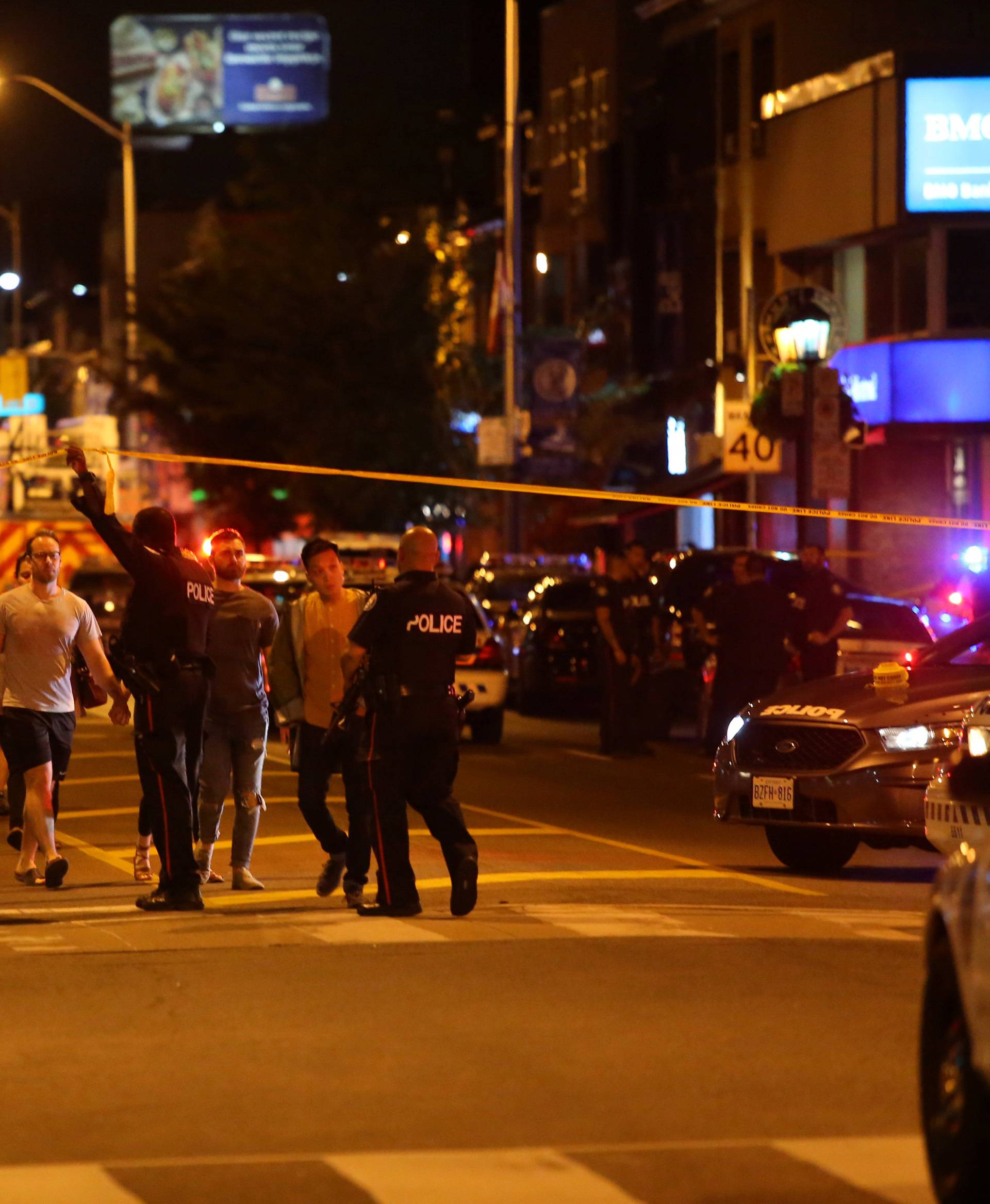 People leave an area taped off by the police near the scene of a mass shooting in Toronto