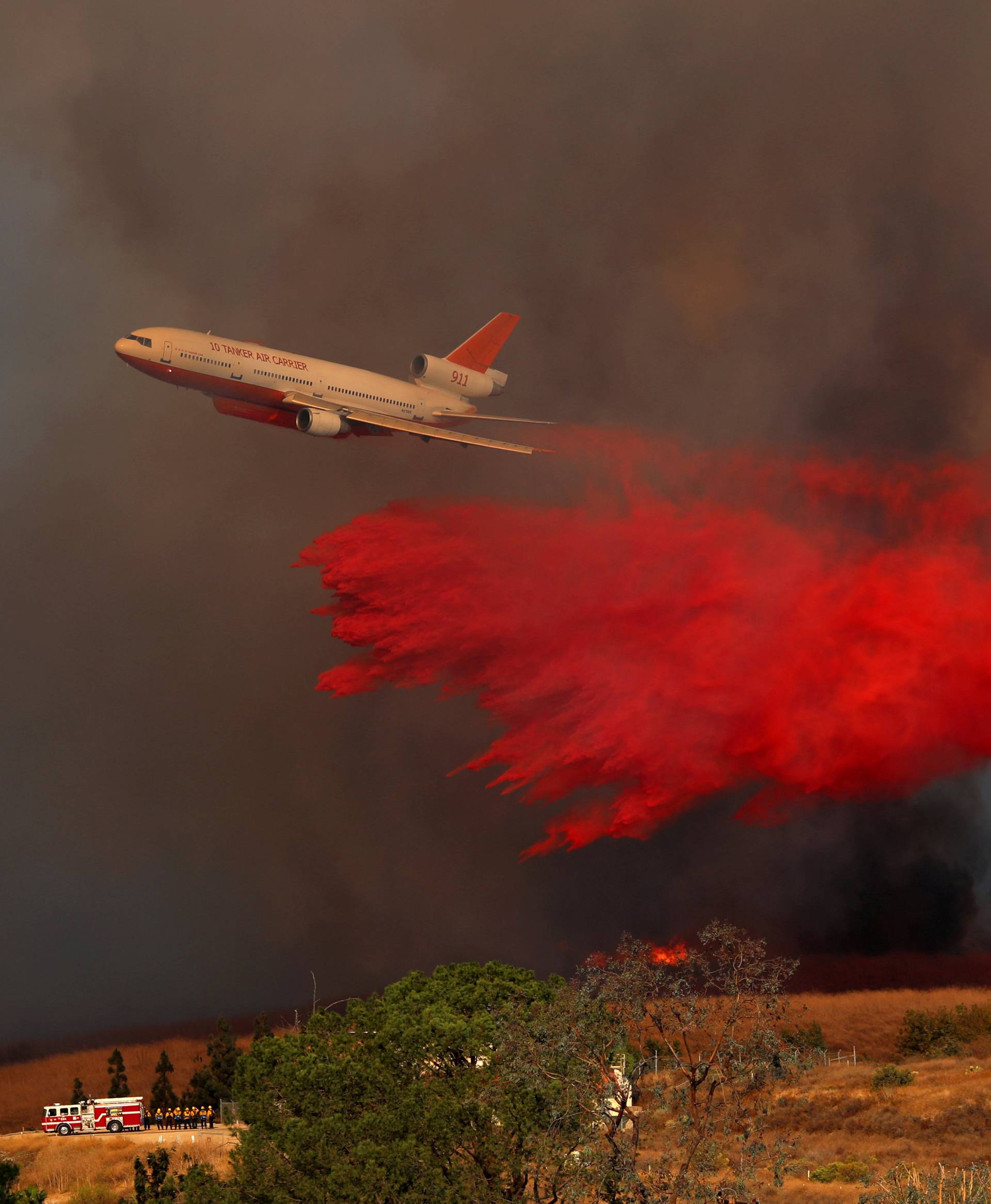 A DC-10 aircraft drops fire retardant on a wind driven wildfire in Orange, California