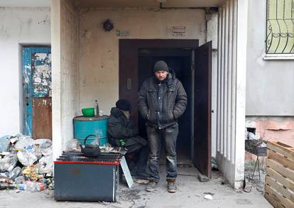 Local residents are seen outside a residential building in the besieged city of Mariupol