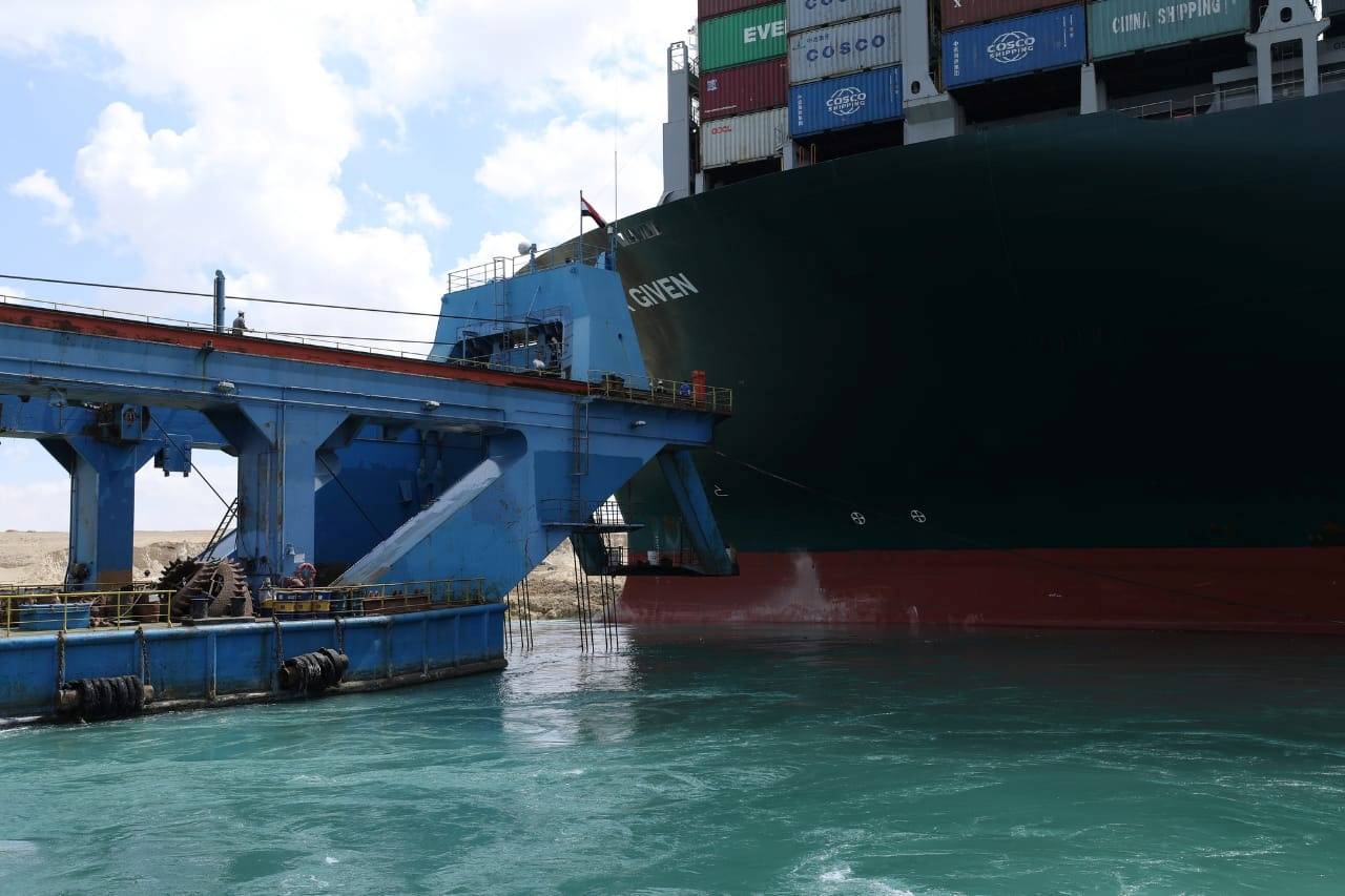 A dredger attempts to free stranded container ship Ever Given, one of the world's largest container ships, after it ran aground, in Suez Canal