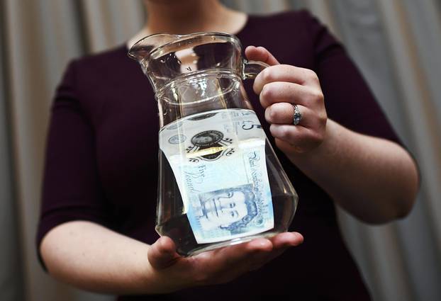 Bank of England Museum curator shows off the waterproof properties of the new polymer five pound note during an event at the Bank of England in London