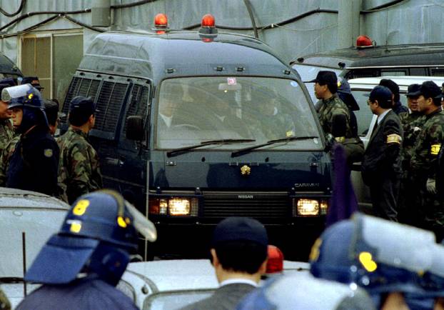 FILE PHOTO : A police vehicle transporting Aum Shinri Kyo sect guru Shoko Asahara is surrounded by policemen as the doomsday prophet is arrested at the cult