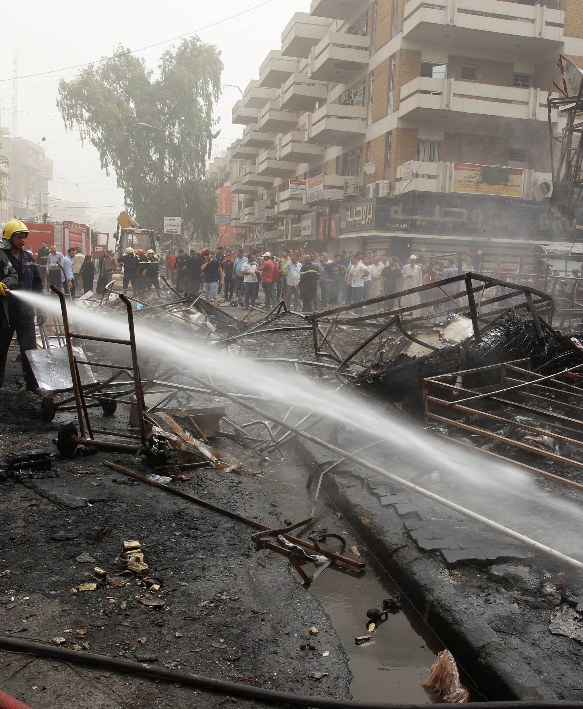 Firemen hose down a burning building as civilians gather after a suicide car bomb occurred in the Karrada shopping area in Baghdad, Iraq