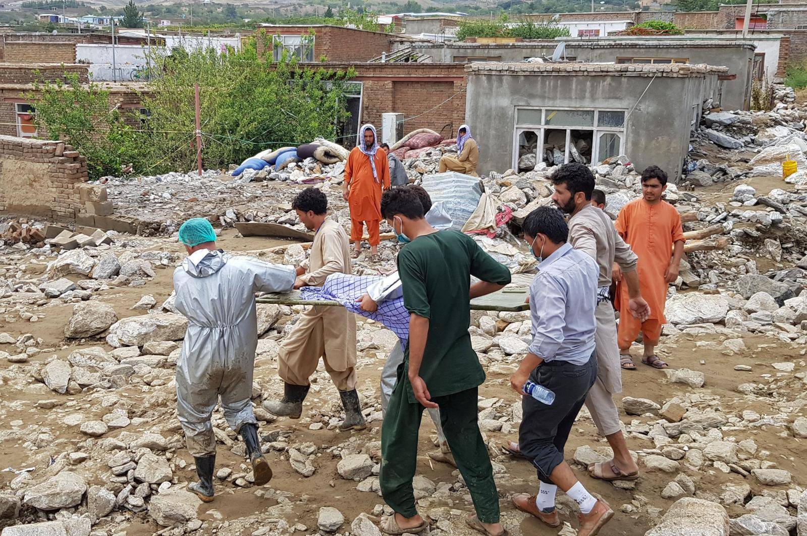 Men carry a victim who died in the floods in Charikar