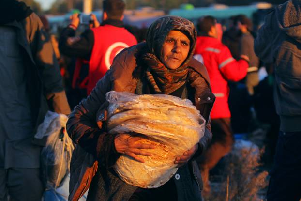 An evacuee from rebel-held east Aleppo carries bread upon her arrival with others at the town of al-Rashideen