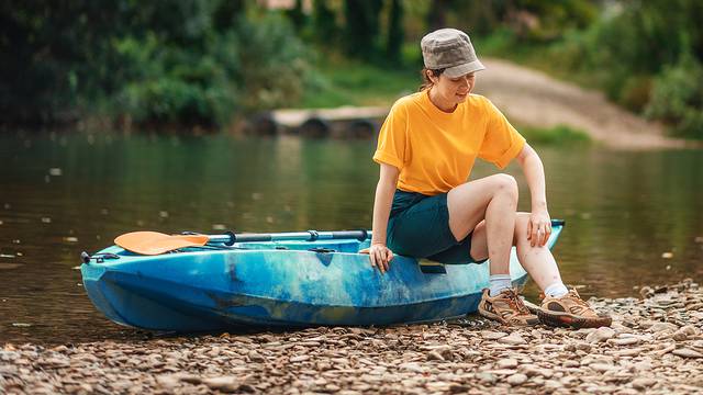 A Young Dissatisfied Woman Is Sitting On A Kayak And Scratching 
