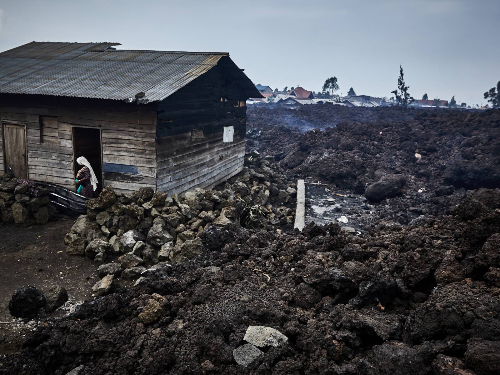 A woman prepares to evacuate from recurrent earth tremors as aftershocks after homes were covered with lava deposited by the eruption of Mount Nyiragongo near Goma