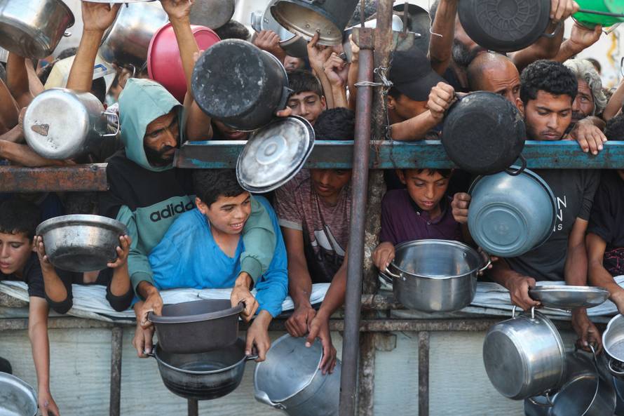 Palestinians wait to receive food from a charity kitchen, amid a hunger crisis, in Gaza City