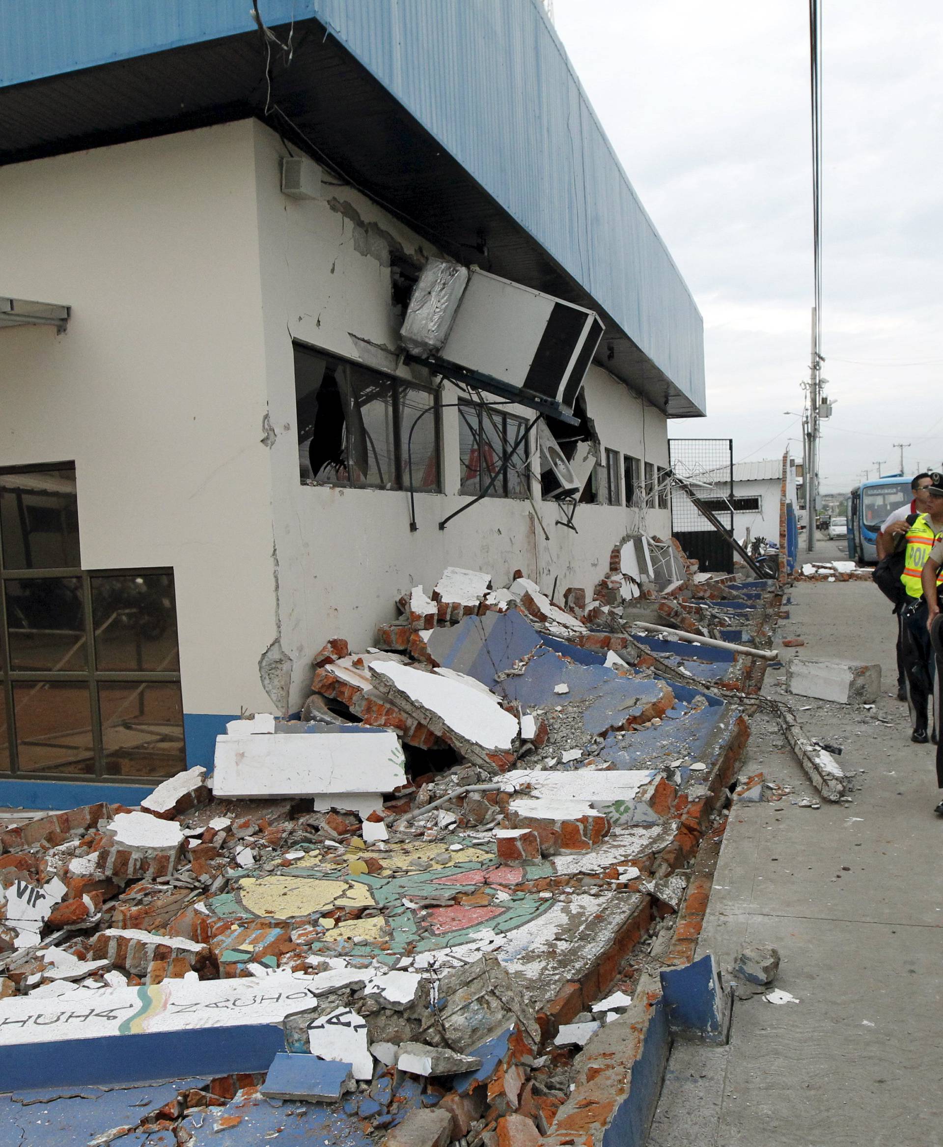 Police officers walk next to debris after an earthquake struck off Ecuador's Pacific coast, at Tarqui neighborhood in Manta