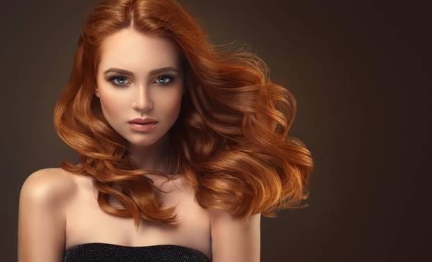 Red haired woman with voluminous, shiny and curly hairstyle.Flying hair.