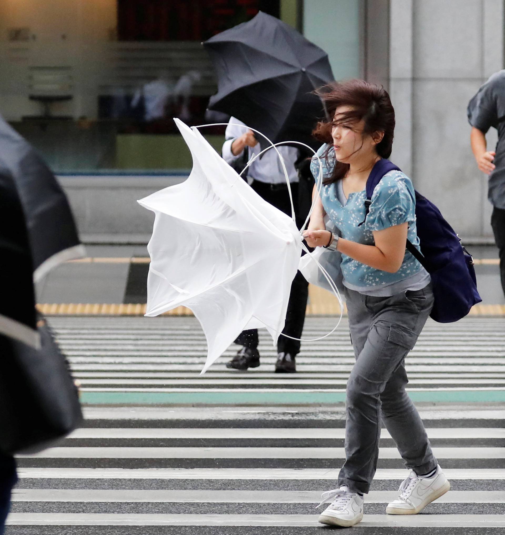 Passersby using umbrellas struggle against strong wind and rain caused by Typhoon Jebi, in Tokyo