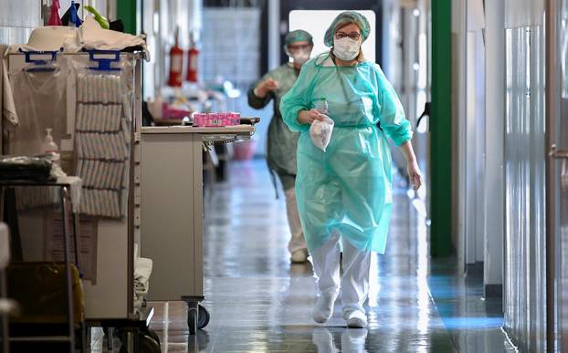 Medical workers wearing protective masks and suits walk in an intensive care unit at the Oglio Po hospital in Cremona