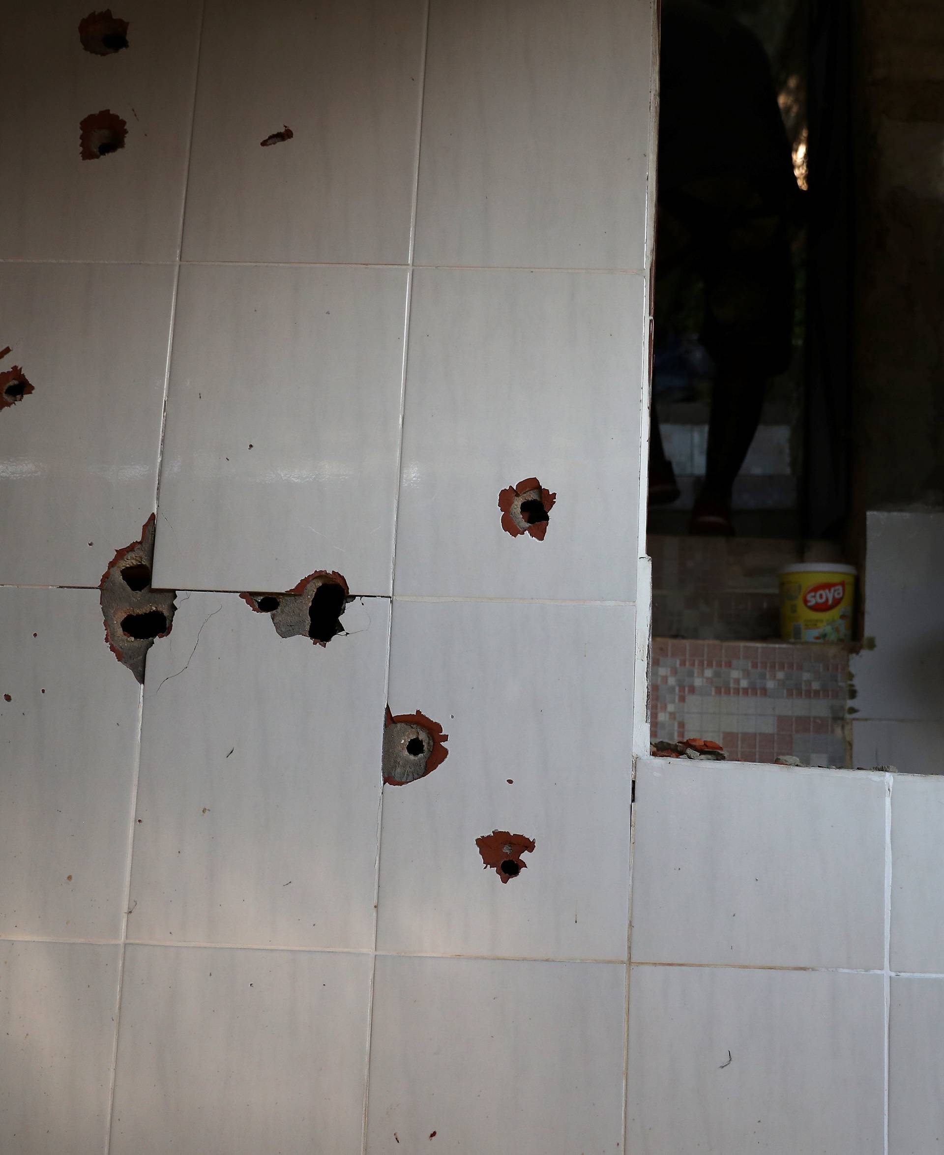 A man is seen next to the wall with bullet holes at a house where police officers confronted suspects during an operation against drug gangs at Fallet slum in Rio de Janeiro