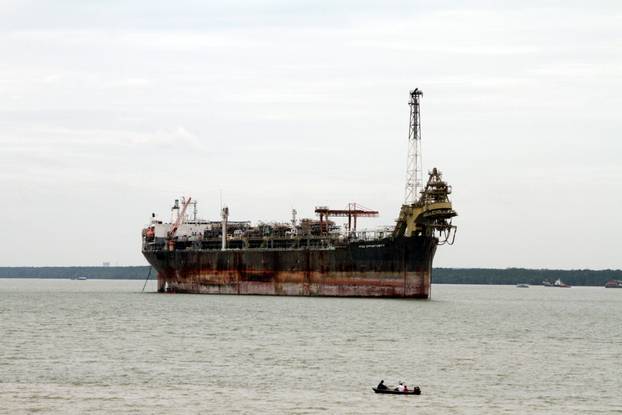 A fishing boat passes in front of the laid-up FPSO Opportunity in the Johor river