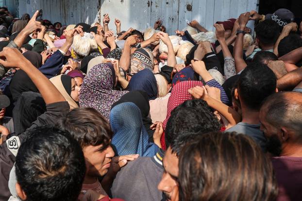 Palestinians gather as they wait to buy bread from a bakery, in Deir Al-Balah, central Gaza Strip
