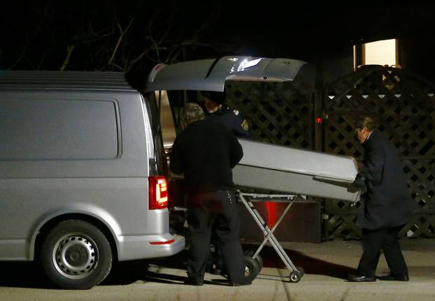 A coffin is loaded nto a hearse outside a house where six people were found dead in Boeheimkirchen
