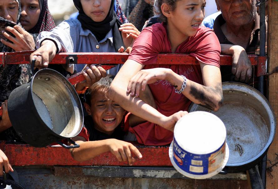 Palestinians wait to receive food from a charity kitchen, in Gaza City