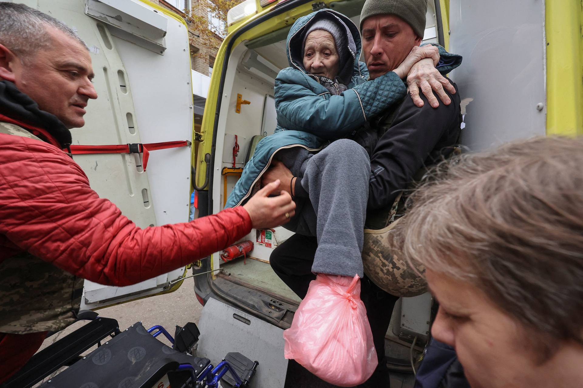 Volunteers carry a Kupiansk resident, who fled due to Russian military strikes, at a compound of an evacuation centre in Kharkiv