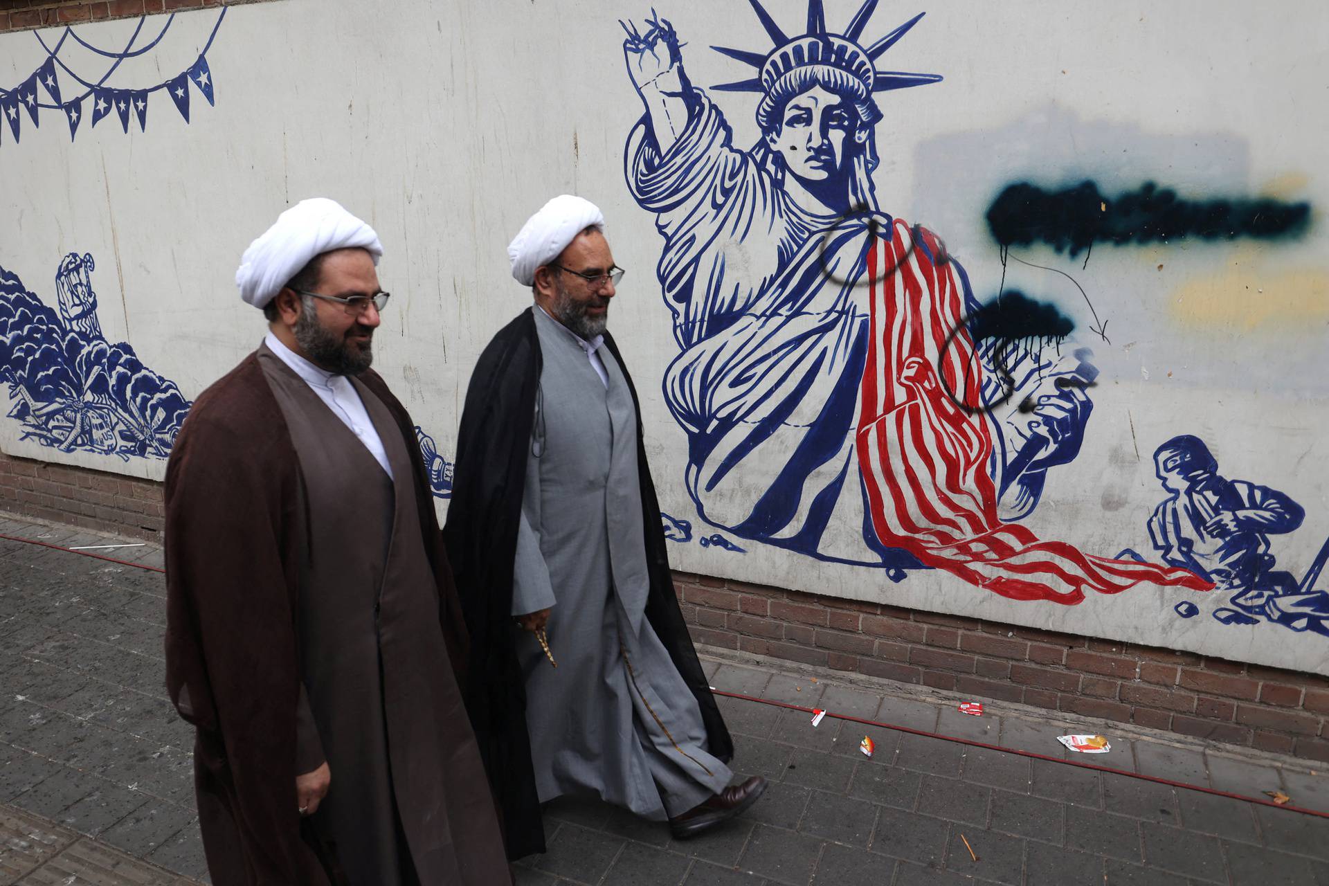 Iranian clerics pass in front of an anti-U.S. mural during the 45th anniversary of the U.S. expulsion from Iran, in Tehran