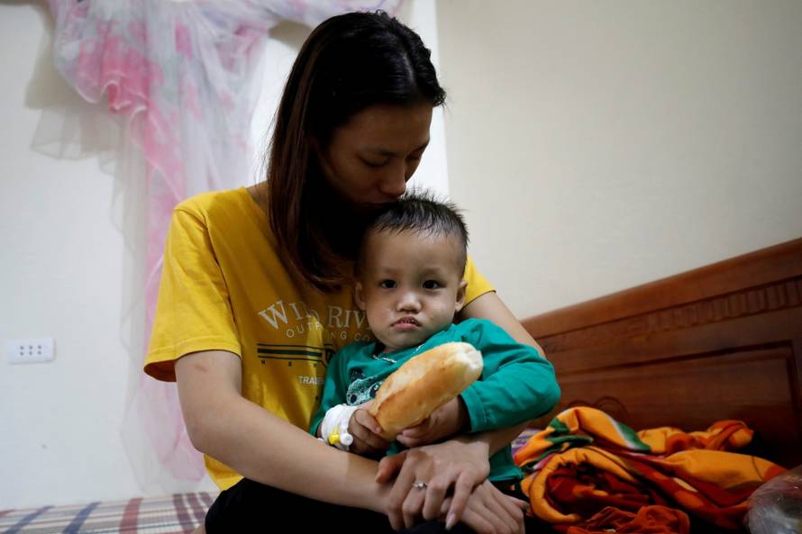Hoang Thi Thuong, wife of Nguyen Dinh Tu, a Vietnamese suspected to be among dead victims found in a lorry in Britain, holds her son Nguyen Dinh Dan at their home in Nghe An province