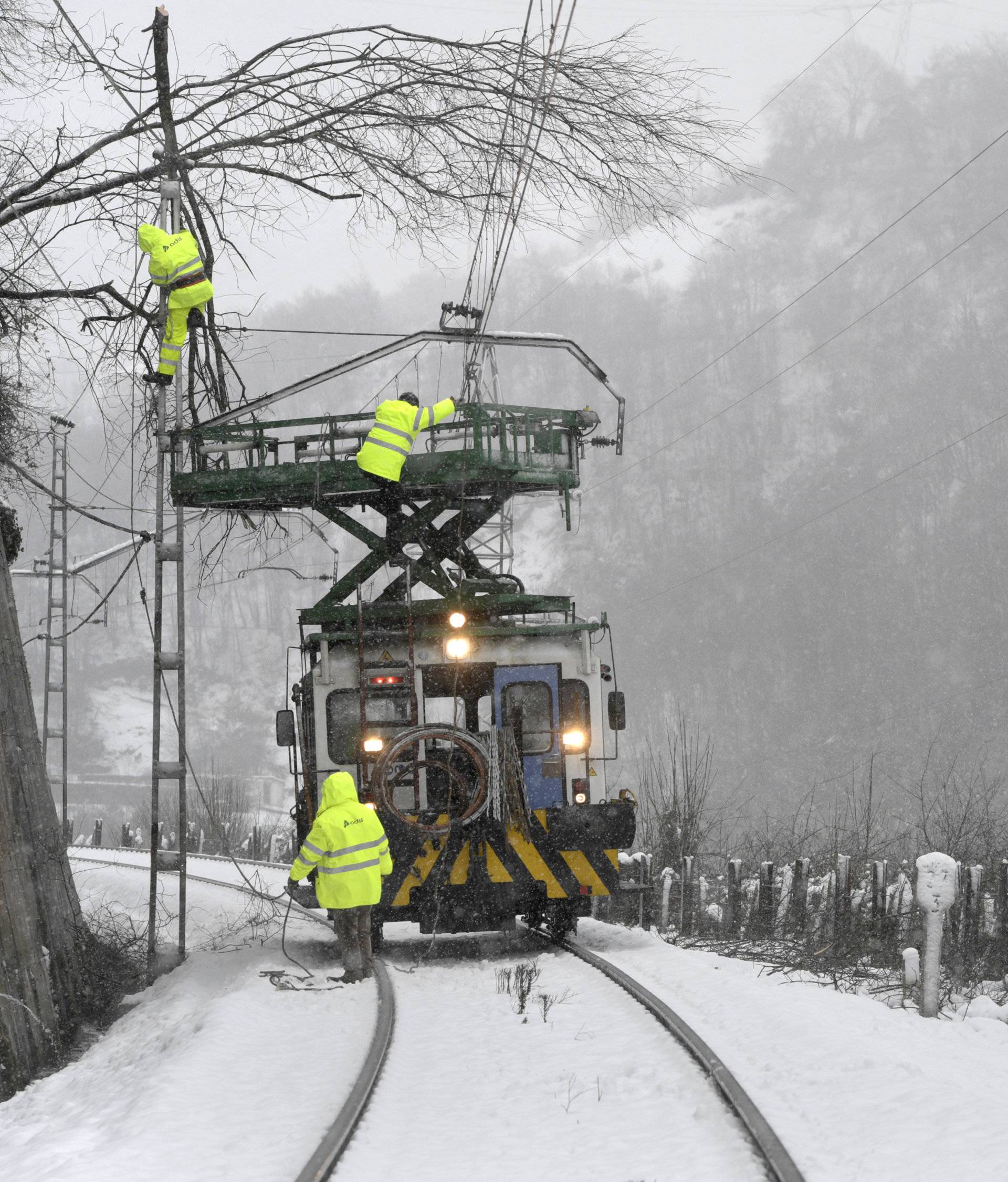 Workers of the railway company ADIF try to clear the railway between Asturias and Leon closed for trains because of the fallen tree branches and snow near Pola de Lena