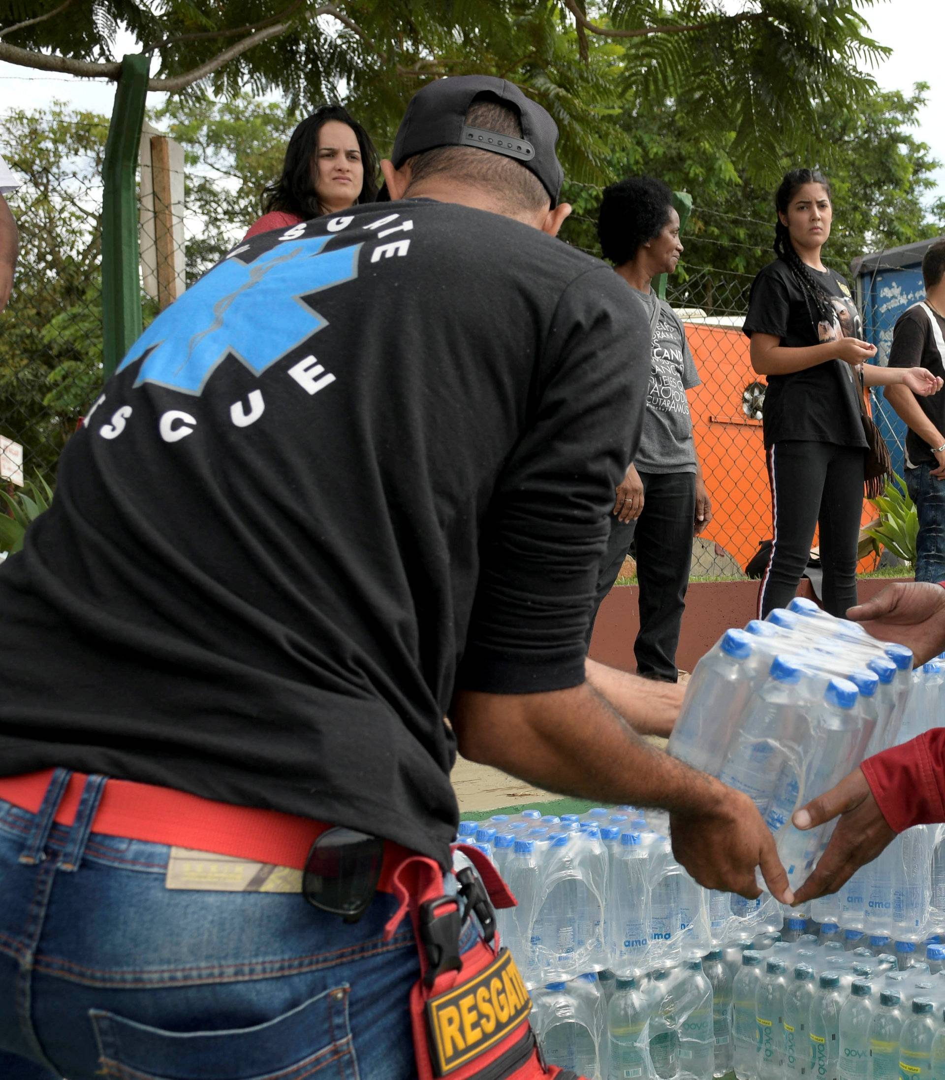 Volunteers pass bottles of water for people affected by a failed iron ore tailings dam owned by Brazilian miner Vale SA that burst, in Brumadinho