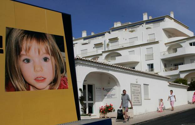 FILE PHOTO - People walk near a billboard at Praia da Luz tourist resort