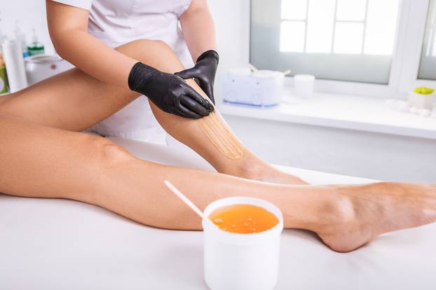 Professional master of wax depilation providing service for client