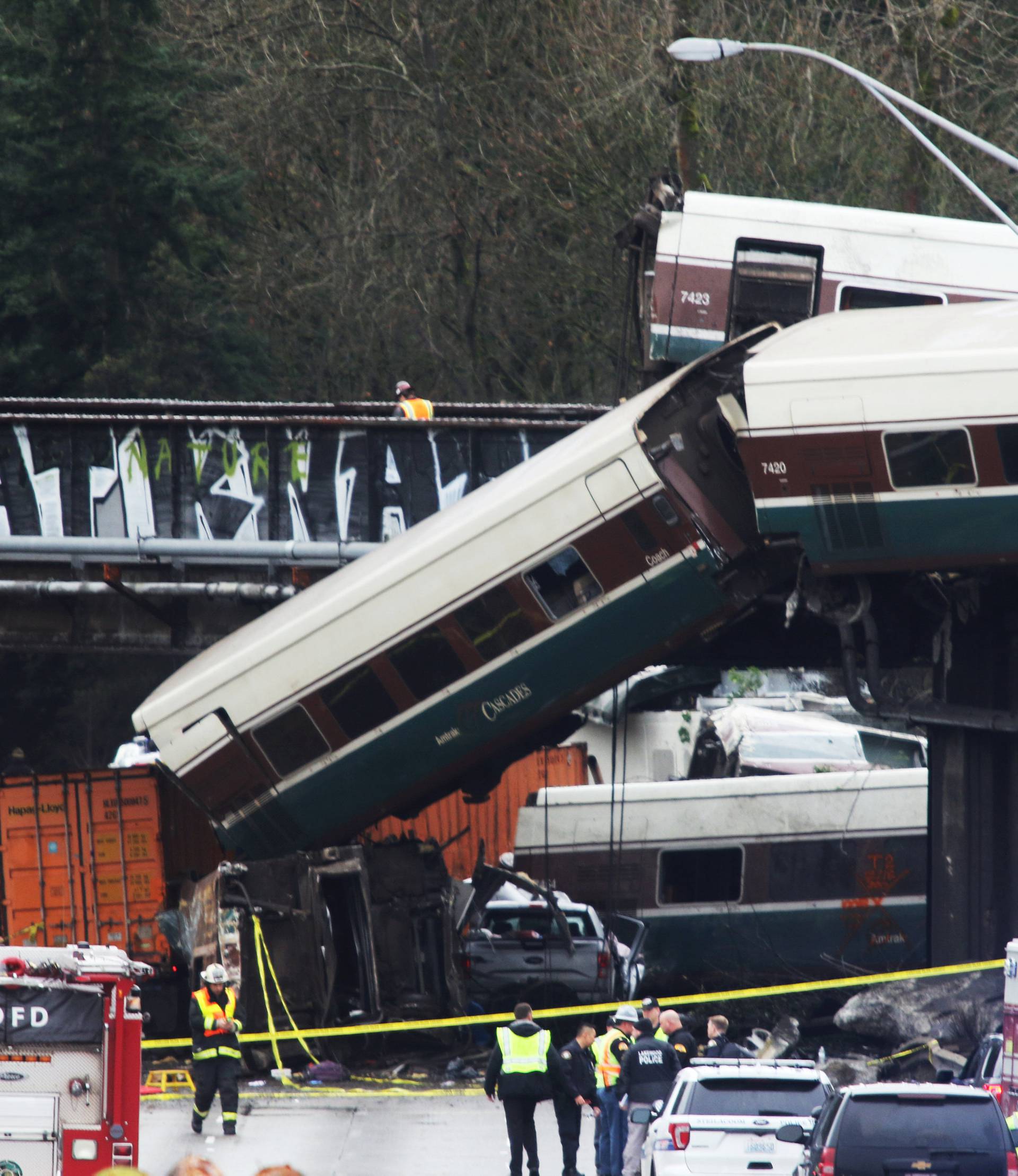First responders are seen at the scene of an Amtrak passenger train which derailed and is hanging from a bridge over the I-5 in DuPont