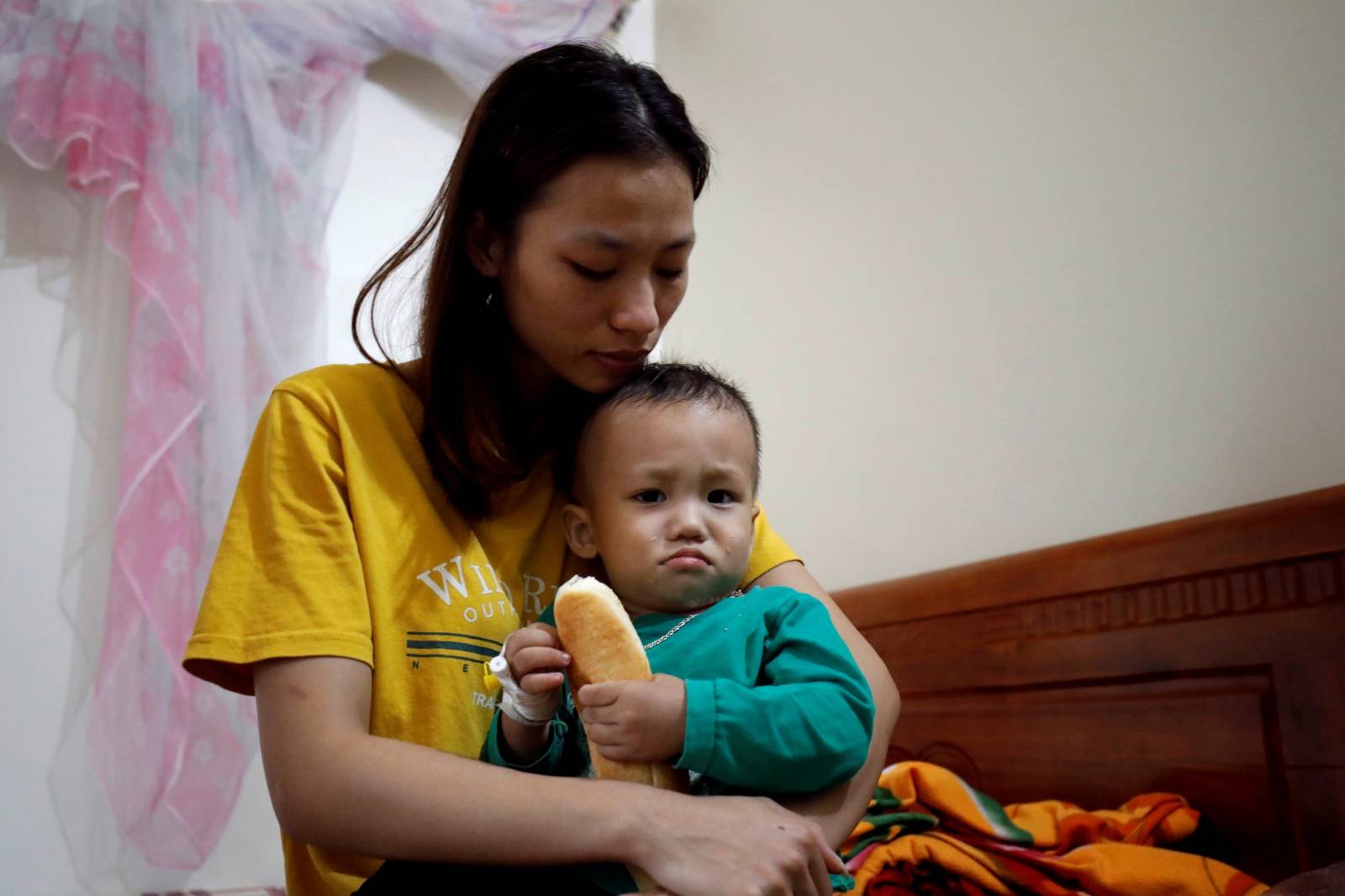 Hoang Thi Thuong, wife of Nguyen Dinh Tu, a Vietnamese suspected to be among dead victims found in a lorry in Britain, holds her son Nguyen Dinh Dan at their home in Nghe An province